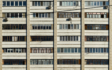 Fototapeta na wymiar Windows and balconies of the residential building. Old urban obsolete facade of house. The windows of an ordinary soviet building.