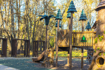 Empty outdoor children's wooden playground with swings in the forest in the autumn outdoors with...