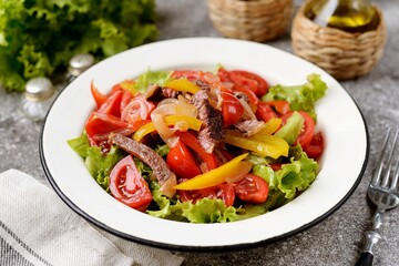 Salad with beef steak, red and yellow peppers, lettuce and cherry tomatoes.