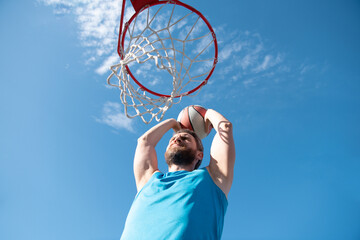 Sports men playing basketball outdoors on a sunny day.