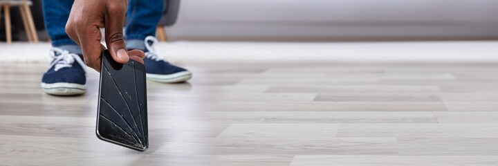Man Picking Up Damaged Mobile Phone