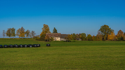 A house with a raked roof. Black hay rolls.