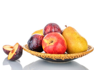 Fresh organic fruits, pear, apple, fig and juicy purple plum on a ceramic dish, close-up, isolated on white.