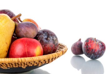 Fresh organic fruits, pear, apple, fig and juicy purple plum on a ceramic dish, close-up, isolated on white.