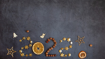 Banner number 2022 of stars, nuts and orange on a dark background. Creative ideas, space for text. Concept Christmas