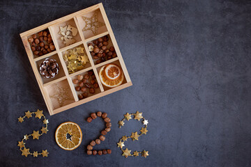 2022 numbers of stars, nuts and oranges with a box filled with Christmas accessories on a dark background.
