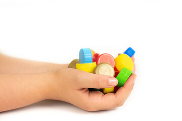 Multi-colored screw caps for plastic bottles in the hands of a child, ecology