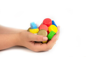 Multi-colored screw caps for plastic bottles in the hands of a child, ecology