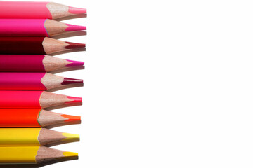 on the left, many pencils of yellow, orange and red colors lie on a white background. top view
