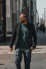 Stylish man with long hair in a suit walking on urban street