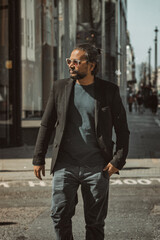 Stylish man with long hair in a suit walking on urban street