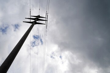 Concrete pylon for high voltage electricity transport and supply. Low angle view with dramatic sky on the background. Copy space available.