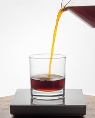 Coffee being poured into clear tumbler against bright backlight