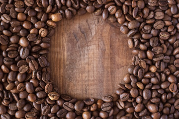 Circle made of coffee beans on a wooden surface close up.