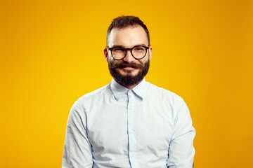 Fototapeta premium Headshot of satisfied cheerful handsome man grins at camera, glad to find suitable well paid job, isolated over yellow background