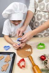 Obraz na płótnie Canvas Happy mother and daughter cutting various shapes of cookies in the kitchen. Mom and daughter make gingerbread cookies at home and have fun. Household, communication, cooking.