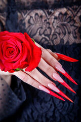 Close-up of female arms and long legs. The girl is holding a crown in her hands. Red nails on a dark background.