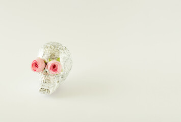 Silver skull with pink roses on bright background. Minimal creative love Halloween concept. Copy space.