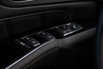 Close up view of button controlling window in modern car interior. Vehicle interior detail. Door handle with windows controls