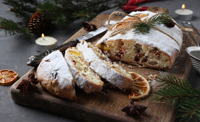 Sliced Christmas stollen with dry fruits, berries and nuts on wooden board. Traditional German...
