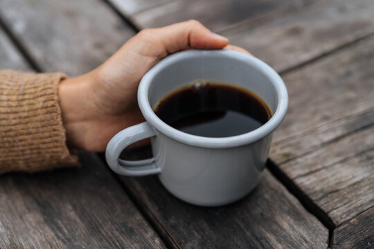 Crop hand with coffee on wooden table