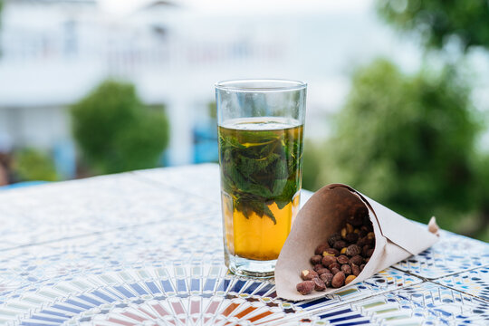 Mint tea in glass and paper bag with fried apricot bones