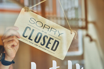 Faceless owner turning signboard on door of store