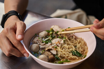 Crop guy eating Thai Noodle Blood soup with pork balls