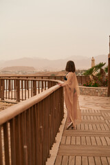 Pretty woman posing in Egypt hotel. Young caucasian woman in black swimsuit and golden dress