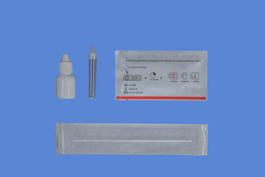 Rapid Covid Corona self test kit or test kit with extraction buffer, buffer tube, unopened test cassette and unopened nasal swab with blue background