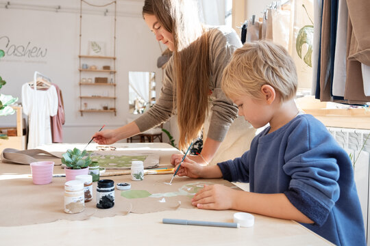 Boy painting on cloth near mother