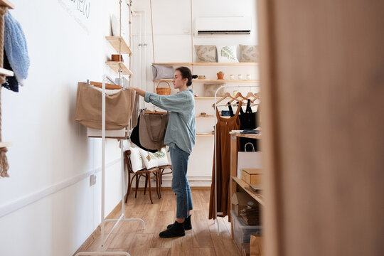 Woman hanging cotton bags on rack