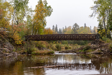 Fototapeta na wymiar Peaceful scene of the bridge going over the Gooseberry River at Gooseberry Falls State Park Minnesota in autumn
