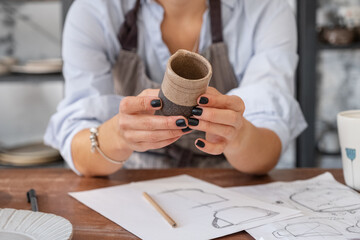 Crop potter examining crockery over sketches