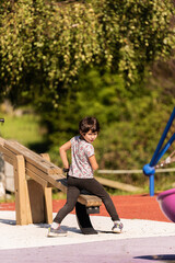 a little girl plays on the seesaw in the children's playground.