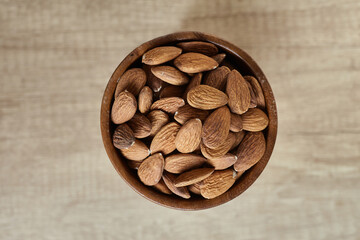 Tasty almond nuts in a bowl on a wooden table, top view. Space for text