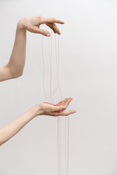 Woman's hand with red threads which symbolized control and manipulation