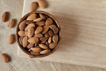 Tasty almond nuts in a bowl on a wooden table, top view. Space for text