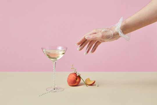 Woman in glove reaching glass with cocktail