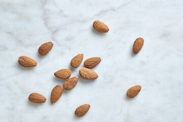 Tasty almond nuts on a barble table, top view. Space for text