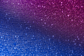 Wavy shimmering blue background. Texture with grain and purple sequins close-up. Gradient two-color...