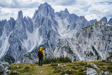 Man hiker standing and admiring stunning beauty of impressive jagged peaks of Cadini di misurina mountain group in Dolomites, Italy, part of Tre Cime di Levaredo national park