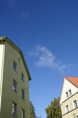 Close up of the yellow houses. Clear blue sky background with some autumn foliage on the back. Bottom up view. Pelgulinna, Tallinn, Estonia, Europe. September 2021