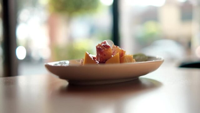 Plate of chopped mango with Mexican chamoy sauce and blurry background