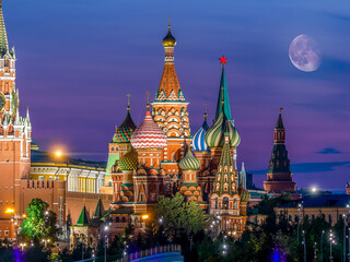 Fototapeta na wymiar St. Basil's Cathedral against the background of the Moscow Kremlin. Colorful evening shot with Moon and purple sky for postcard or calendar. Famous tourist attraction of Russia