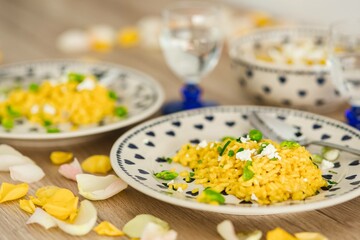 Yellow rice with greens on a cute plate with blue hearts and a table decorated with flower petals