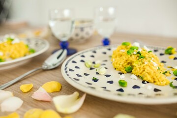 Yellow rice with greens on a cute plate with blue hearts and a table decorated with flower petals