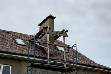 Scaffolding on the roof of the house, the construction of a chimney.