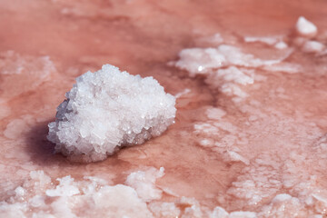Large crystals of medicinal salt on surface of salty pink lake, close-up. Selective focus. Useful product used in cosmetology and alternative medicine