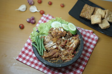 Ayam penyet (smashed fried chicken) is Indonesian East Javanese cuisine, served with sambal chili, lettuce and cucumber slice.